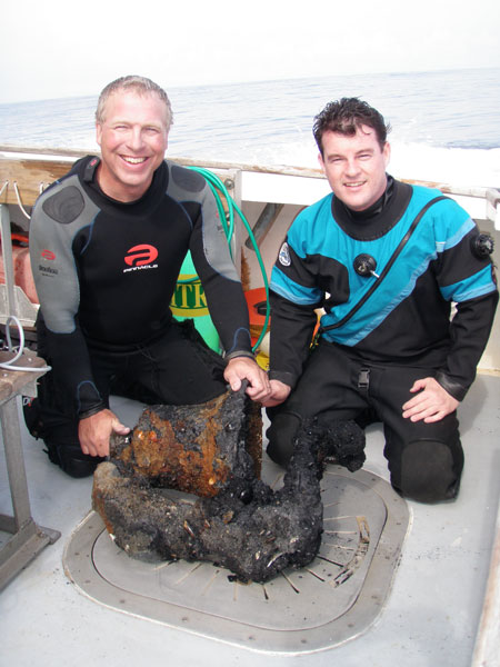 Divers who recovered the bell from the Proteus wreck display it on the deck of the Lion's Paw.